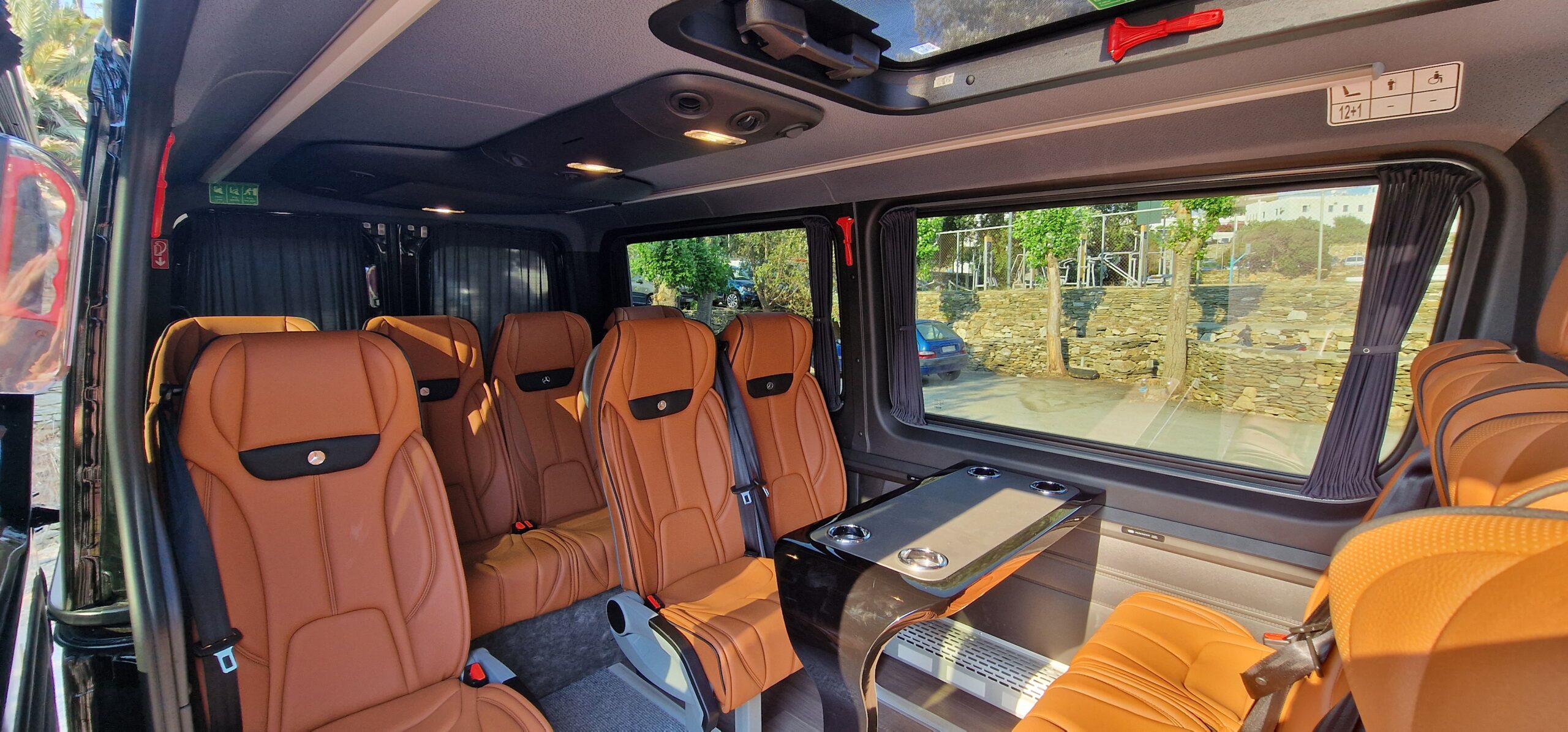 Luxury Mercedes-Benz Sprinter VIP cabin interior with cognac leather executive seating and a piano-black conference table.