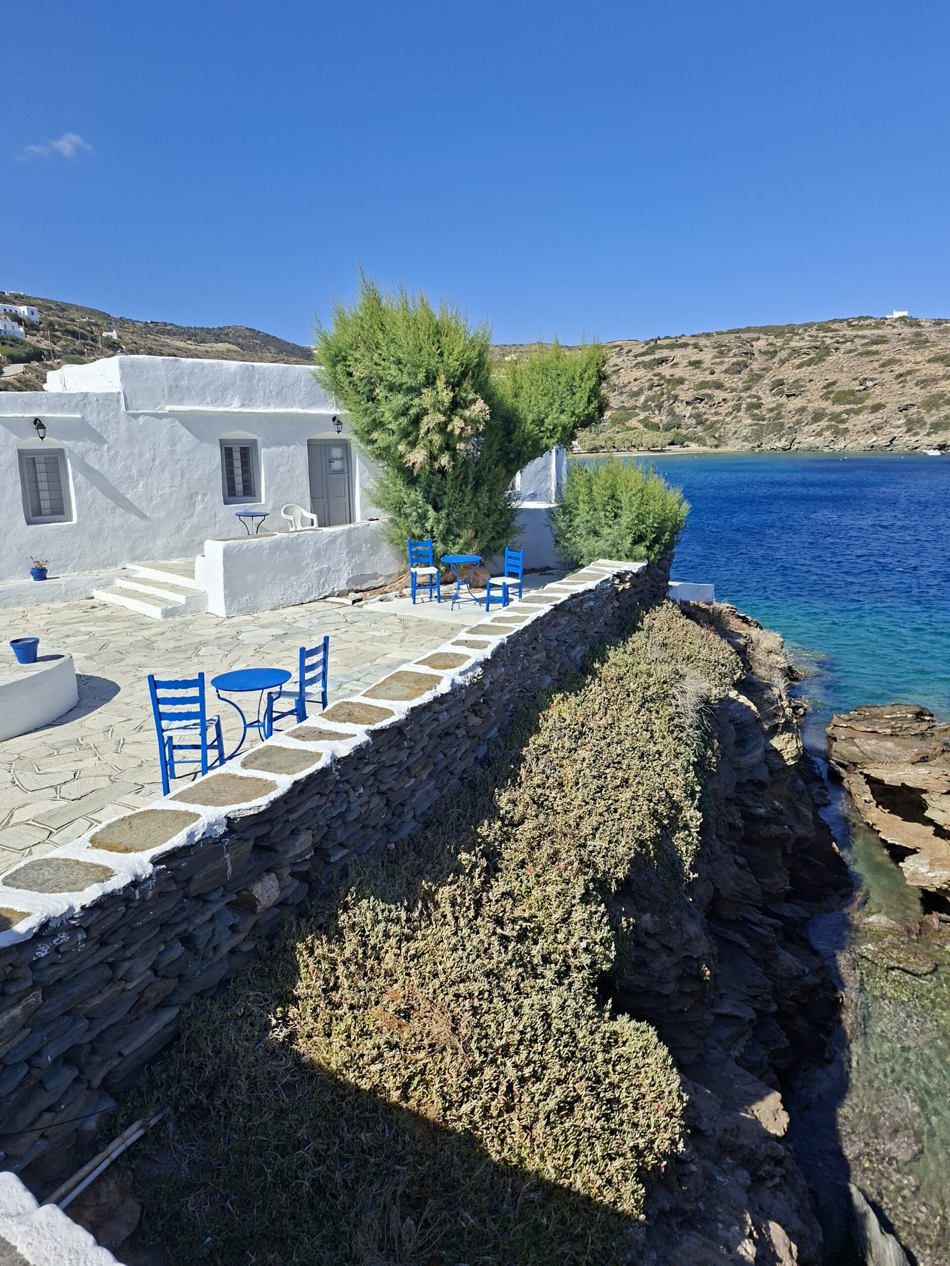 Traditional Cycladic whitewashed seaside terrace overlooking a turquoise cove during a beach and village exploration tour in Sifnos