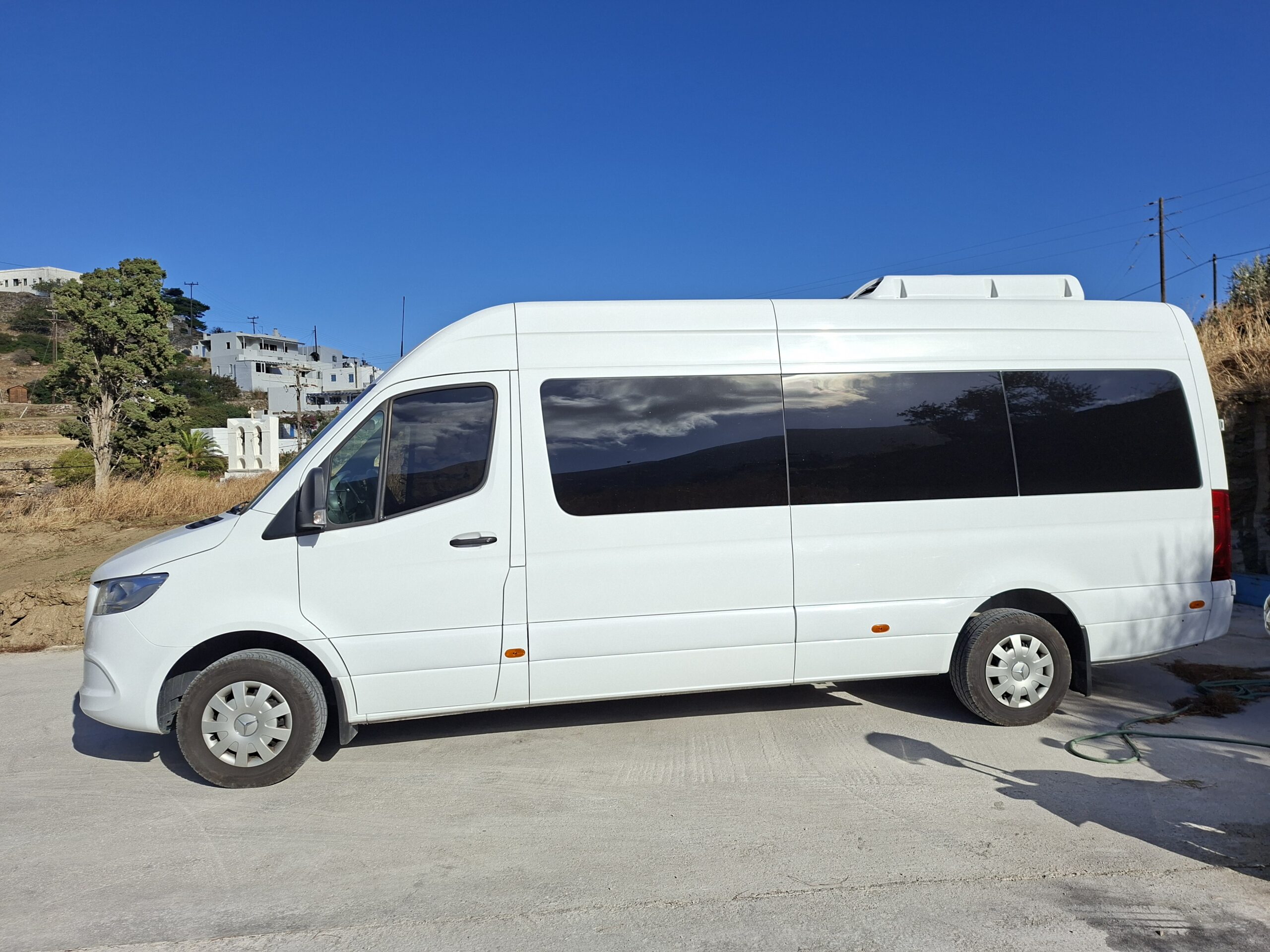White Mercedes-Benz passenger van parked in a sunny Cycladic village during a full-day private tour in Sifnos