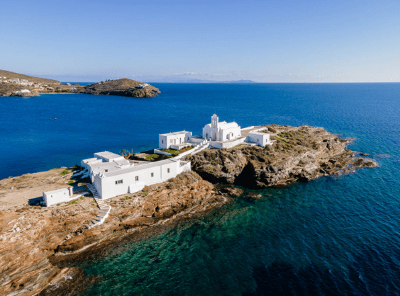 Aerial view of Panagia Chrysopigi monastery on its rocky peninsula and turquoise sea on Sifnos