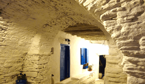 Whitewashed stone passageway with arches and blue doors in Kastro, Sifnos