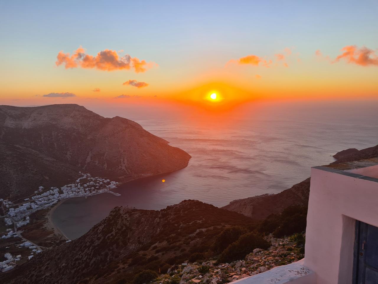 Cycladic chapel silhouette against a golden sunset over the Aegean sea